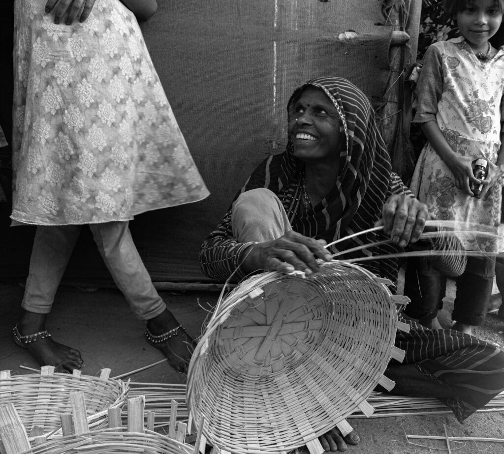 A woman weaving bamboo basket with her hands.